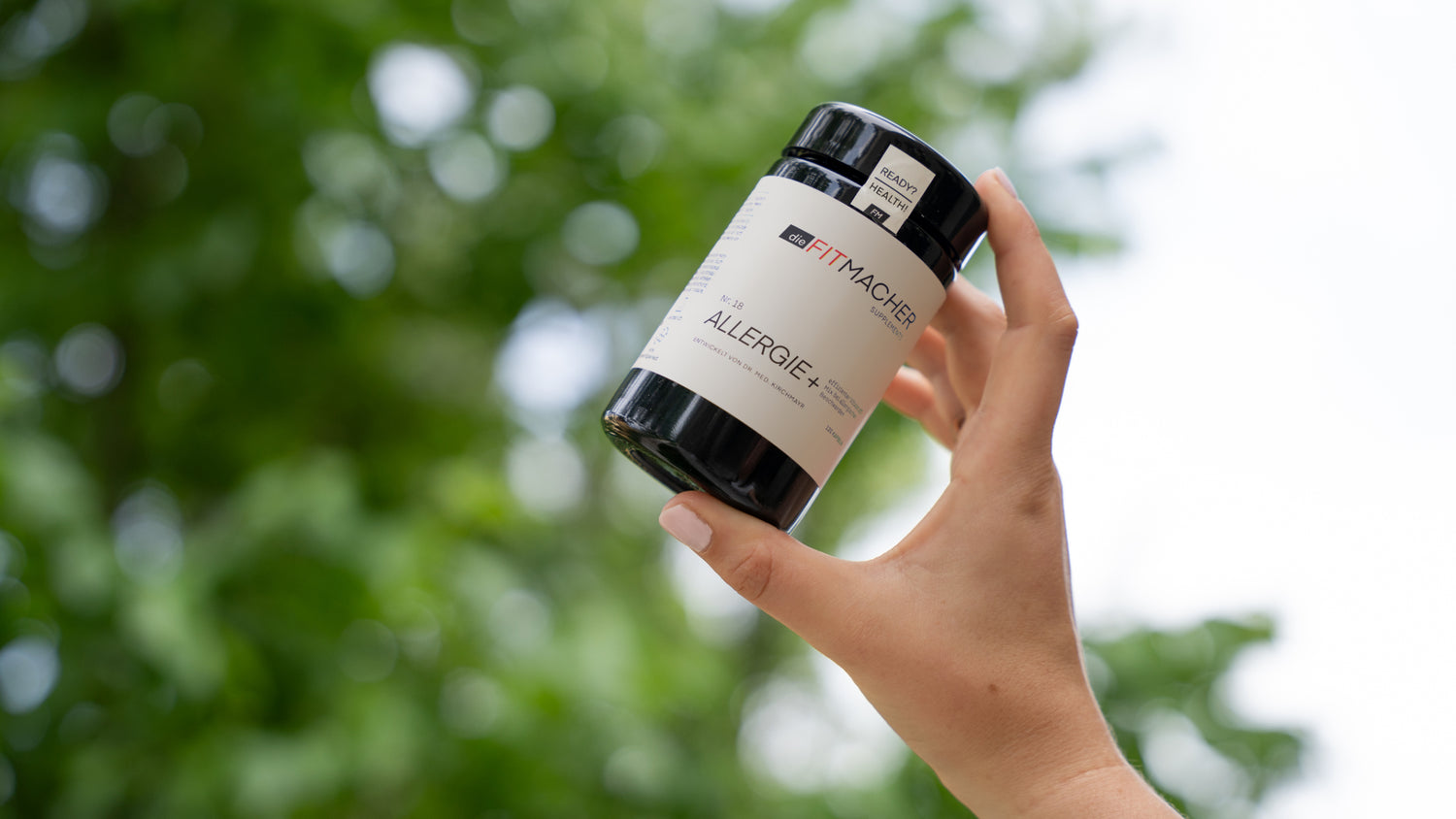 Hand hält Allergie+ Behälter