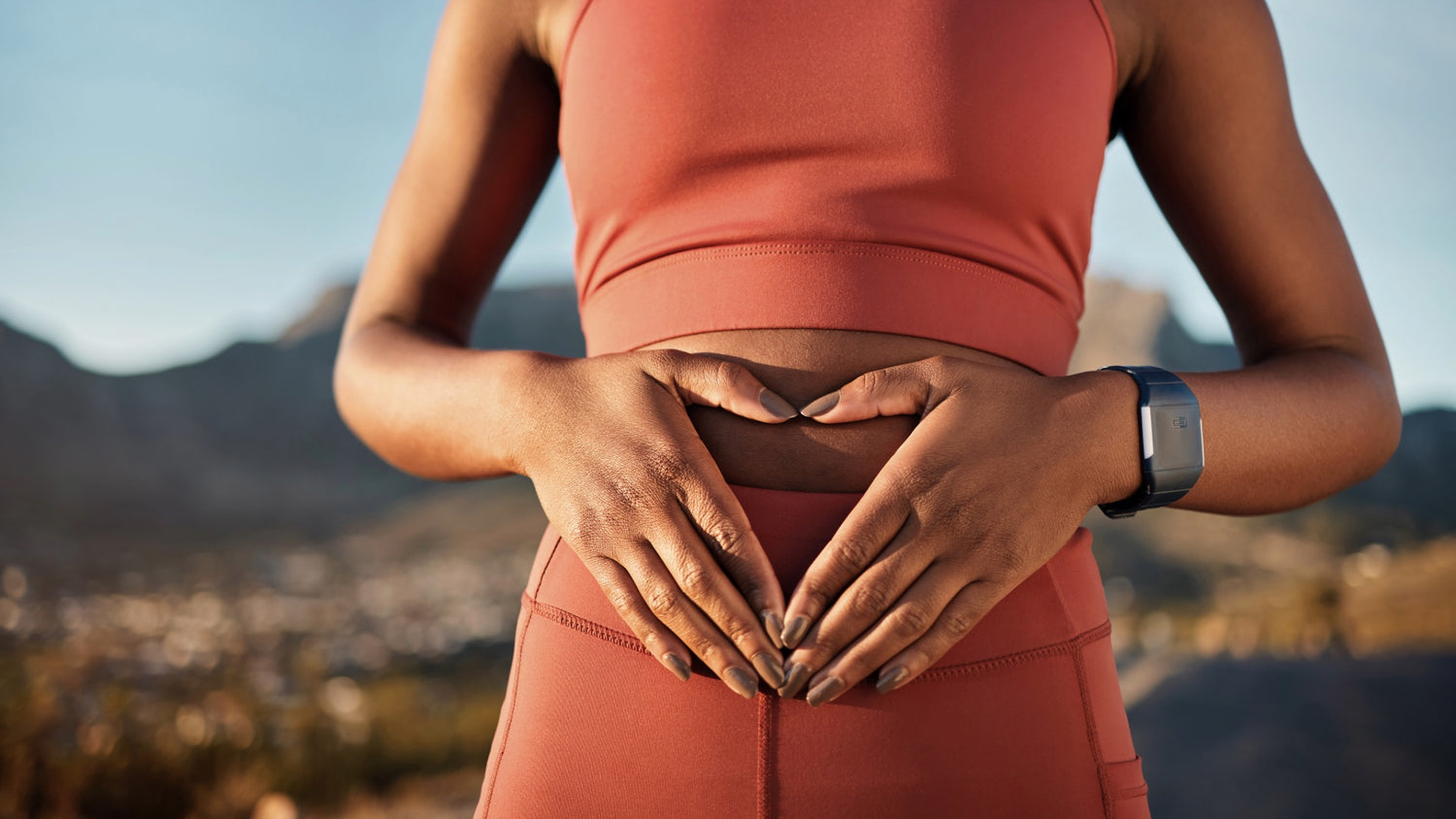 Frau formt ein Herz mit Händen auf dem Bauch