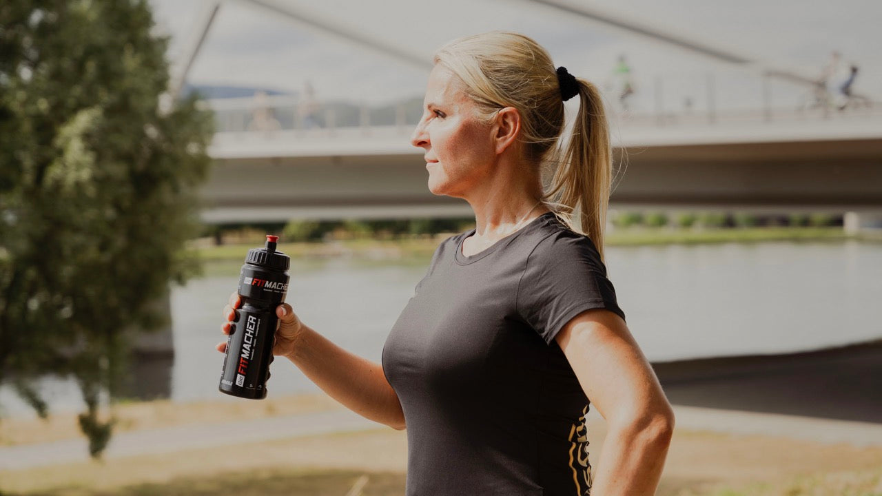 Frau hält dieFitmacher Trinkflasche in der Hand