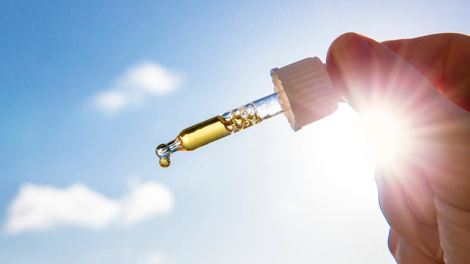 Hand tropft Vitamin D aus Behälter